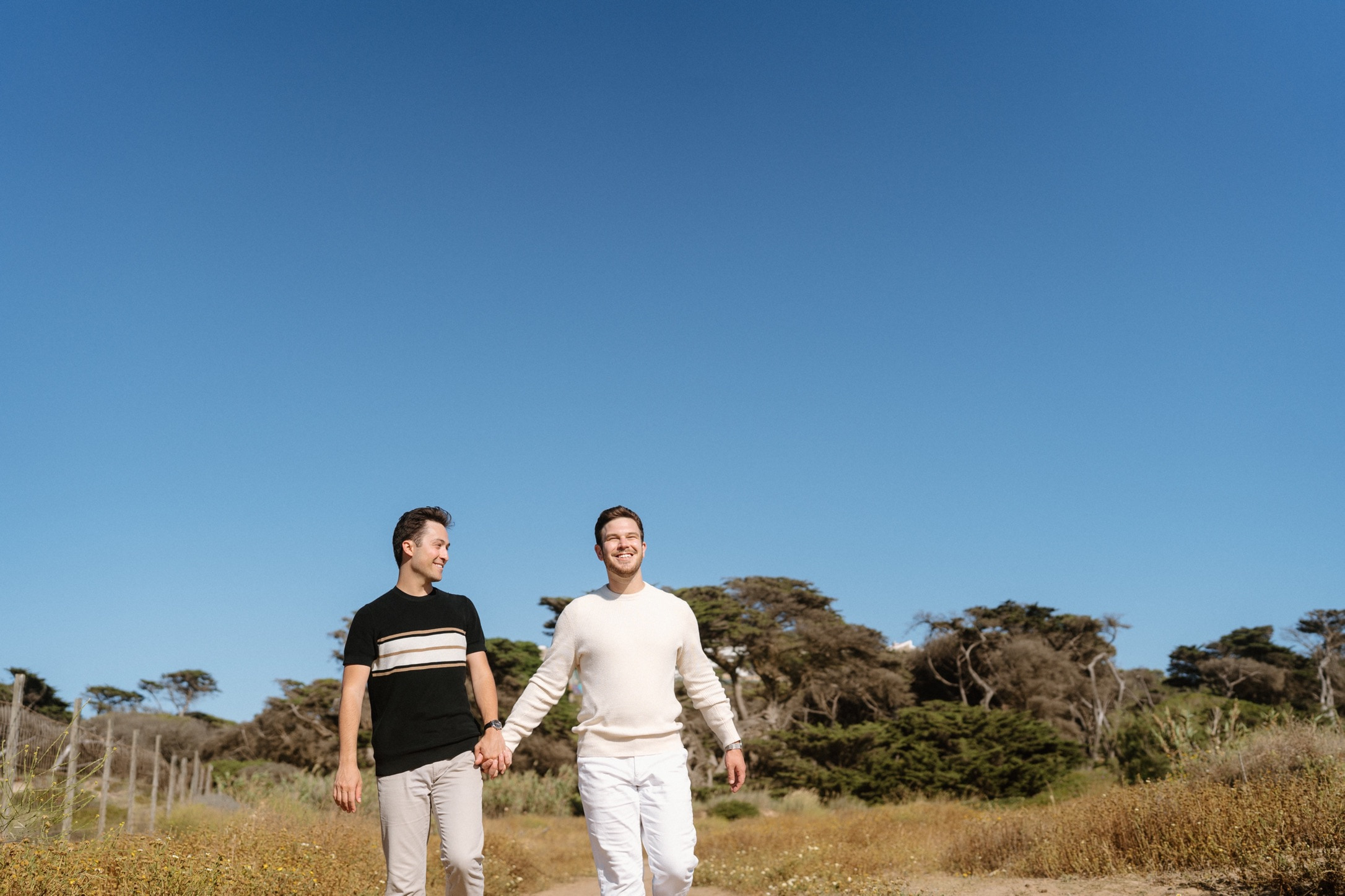 Phil and Zack walking hand in hand during their engagement photos in Portugal